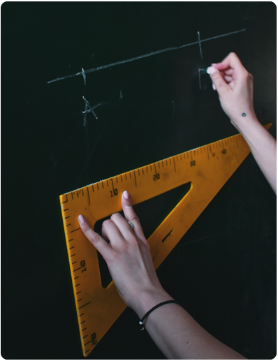 A teacher writing on a blackboard holding a set square - medmark teachers
