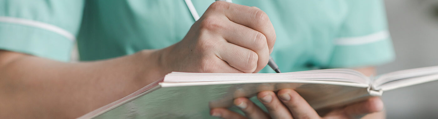 A doctor taking notes in a hard copy notebook