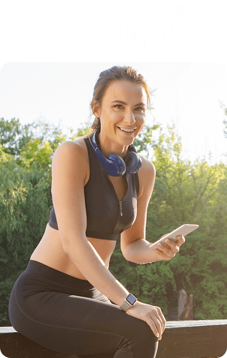 Medmark Wellness a female in workout clothes holding her phone